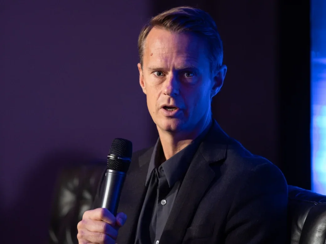 Luke Bradley-Jones, president of The Economist, speaking on stage holding a microphone