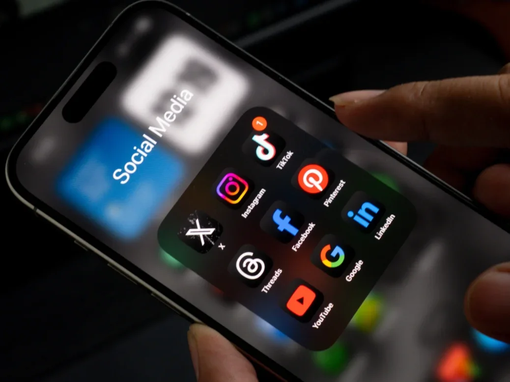 Social media app folder on a phone, featuring icons for X, Instagram, Tiktok, Threads, Facebook, Pinterest, Youtube, Google and Linkedin